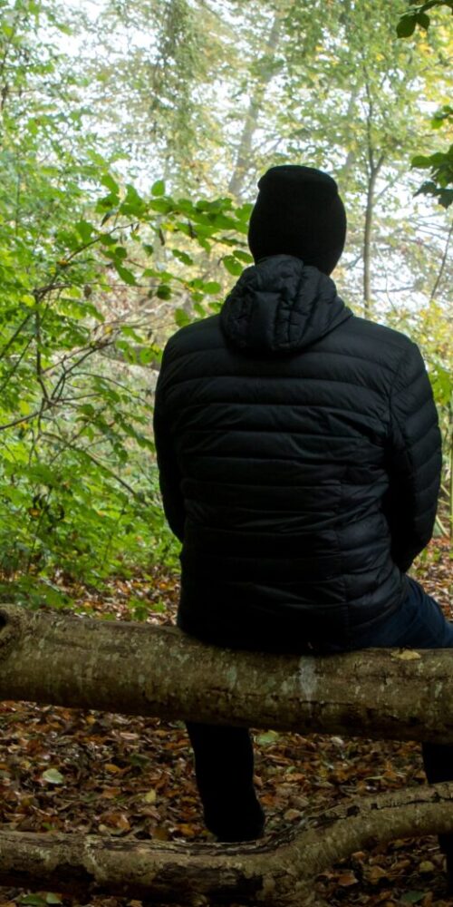 Person sitting quietly in nature, looking thoughtful and reflective